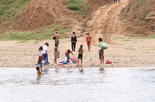 Nhóm học sinh cấp một mặc lại áo quần sau khi lội qua sông. Ảnh:Th.Hiếu