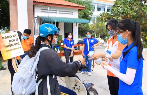 Lực lượng sinh viên tình nguyện tham gia hỗ trợ đo thân nhiệt, xịt nước rửa tay khử khuẩn cho thí sinh
