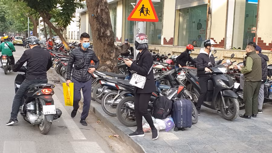 Trên phố Quán Sứ, những điểm trông xe đã lấn hết vỉa hè, khiến người đi bộ phải tràn xuống lòng đường