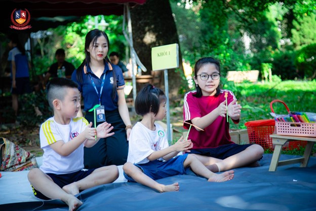 Thanh Trúc hướng dẫn các em nhỏ làm chong chóng. (Ảnh: Vietschool) Thanh Trúc hướng dẫn các em nhỏ làm chong chóng. (Ảnh: Vietschool)