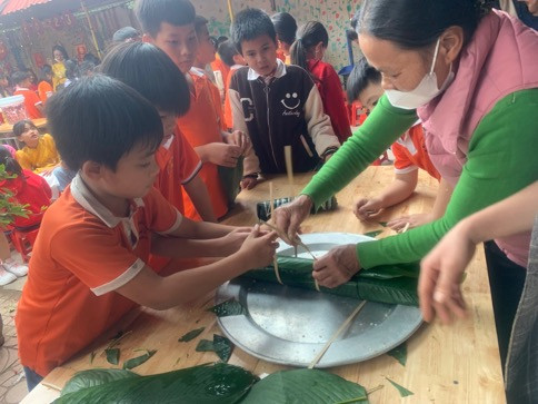 Đại biểu và phụ huynh hướng dẫn học sinh thực hiện từng bước làm bánh Đại biểu và phụ huynh hướng dẫn học sinh thực hiện từng bước làm bánh