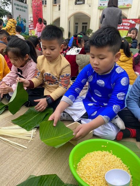 Các em diện áo dài, sắp xếp lá dong, chuẩn bị gói bánh.