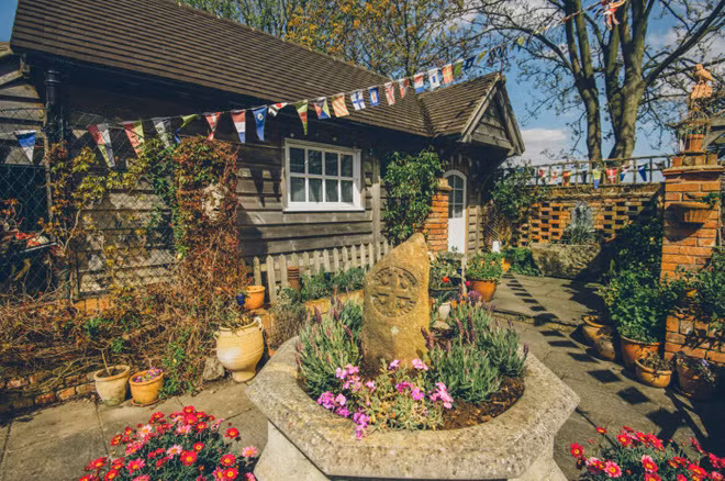 Phần sân sau nhà với hoa lá rực rỡ, tượng trang trí, đài phun nước. Hiện ngôi nhà mở cửa đón du khách vào xem. Ảnh: House Beautiful