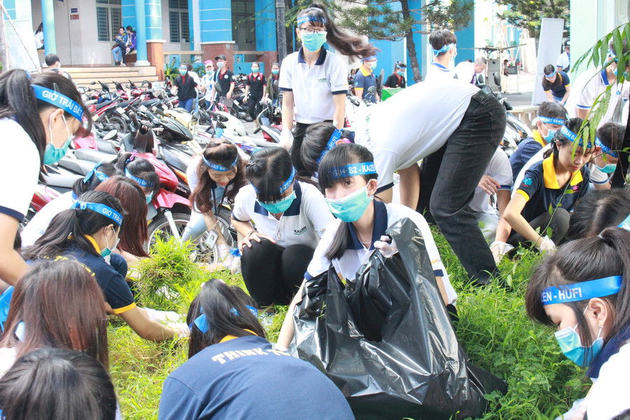 Các sinh viên, học sinh cùng dọn dẹp rác, nhổ cỏ trong sân trường