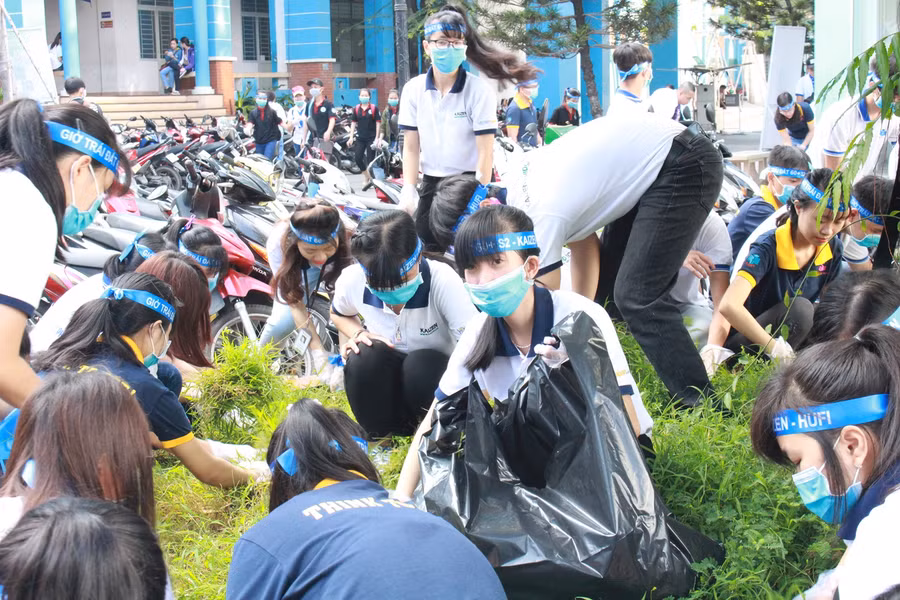Các sinh viên, học sinh cùng dọn dẹp rác, nhổ cỏ trong sân trường