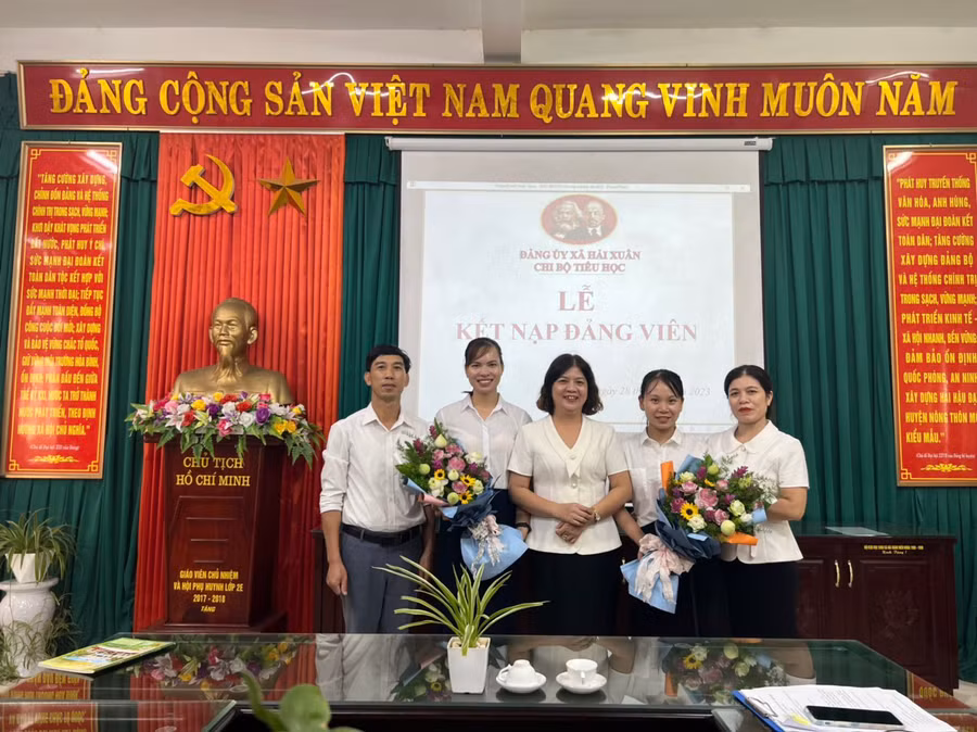 Cô Đinh Thị Hằng Nga (giữa) cùng đại diện Chi bộ nhà trường tặng hoa chúc mừng các tân đảng viên.