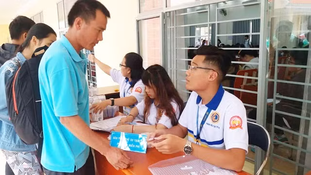 Sinh viên tình nguyện của nhà trường phát phiếu suất ăn miễn phí cho phụ huynh, tân sinh viên có nhu cầu