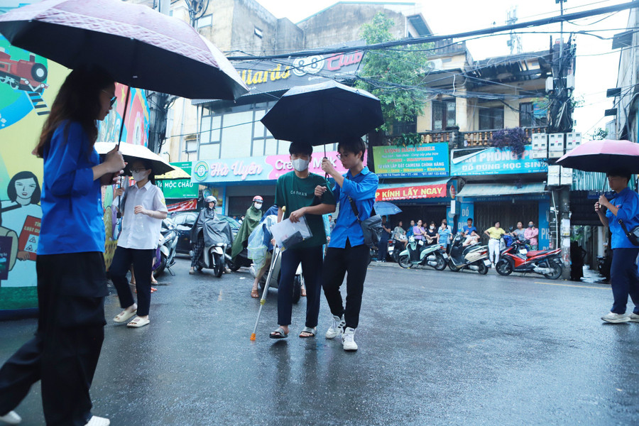 Một thí sinh bị đau chân phải chống nạng được đoàn viên thanh niên hỗ trợ từ cổng. Một thí sinh bị đau chân phải chống nạng được đoàn viên thanh niên hỗ trợ từ cổng.