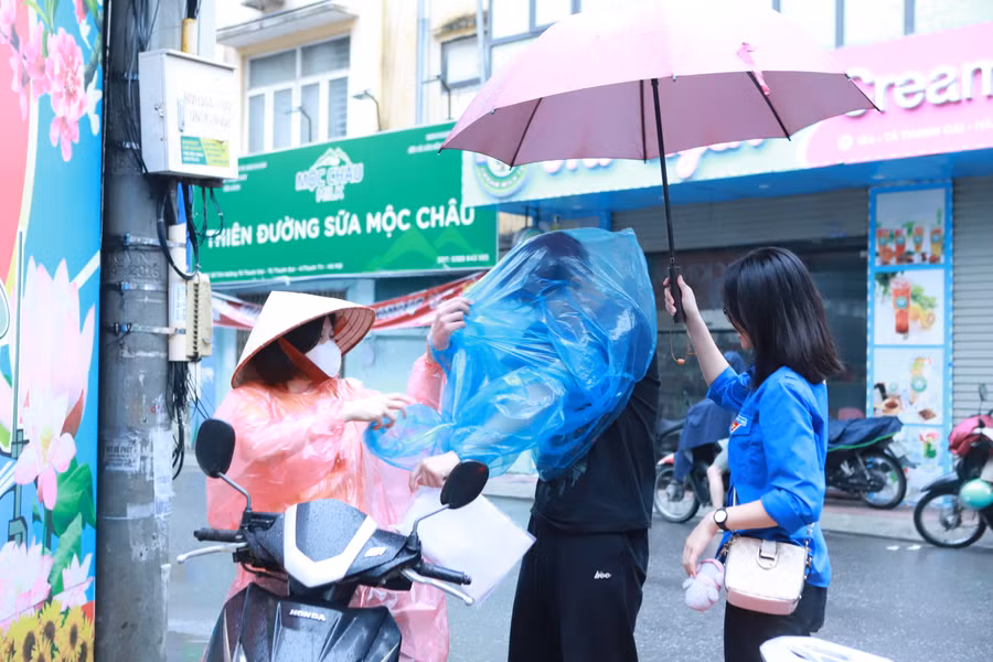 Thí sinh được người nhà đưa đến điểm thi và được thanh niên che ô từ tận cổng.