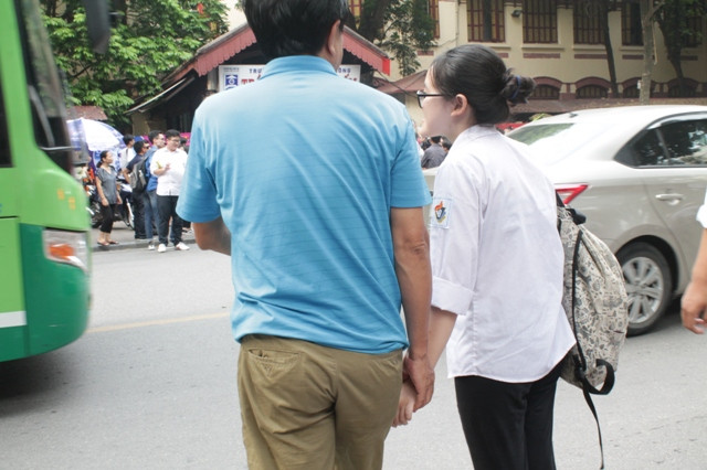 Ông bố này luôn nắm tay con gái từ cổng trường thi qua đường