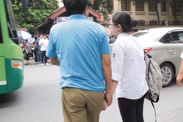 Ông bố này luôn nắm tay con gái từ cổng trường thi qua đường