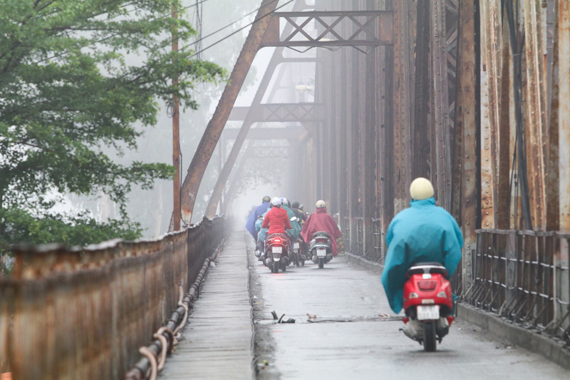 Nhiều người đi trên cầu phải mặc áo mưa