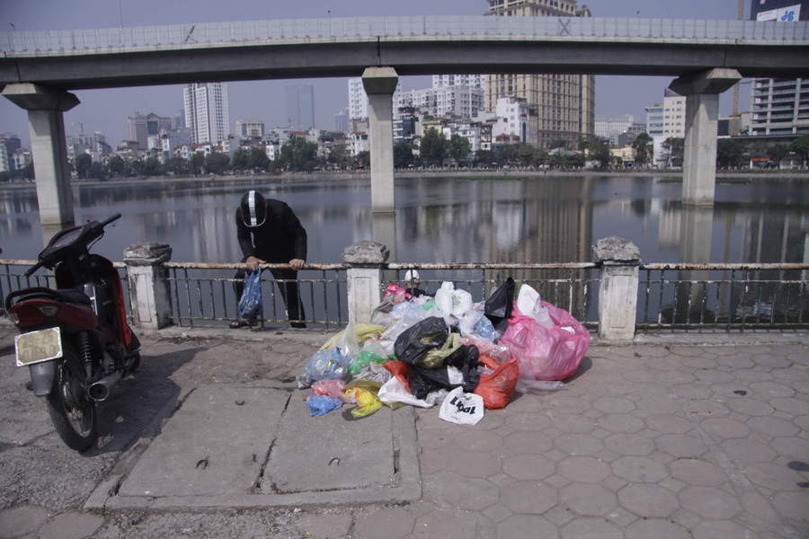 Trên vỉa hè cạnh hồ, túi nilon được chất thành đống gây mất mỹ quan
