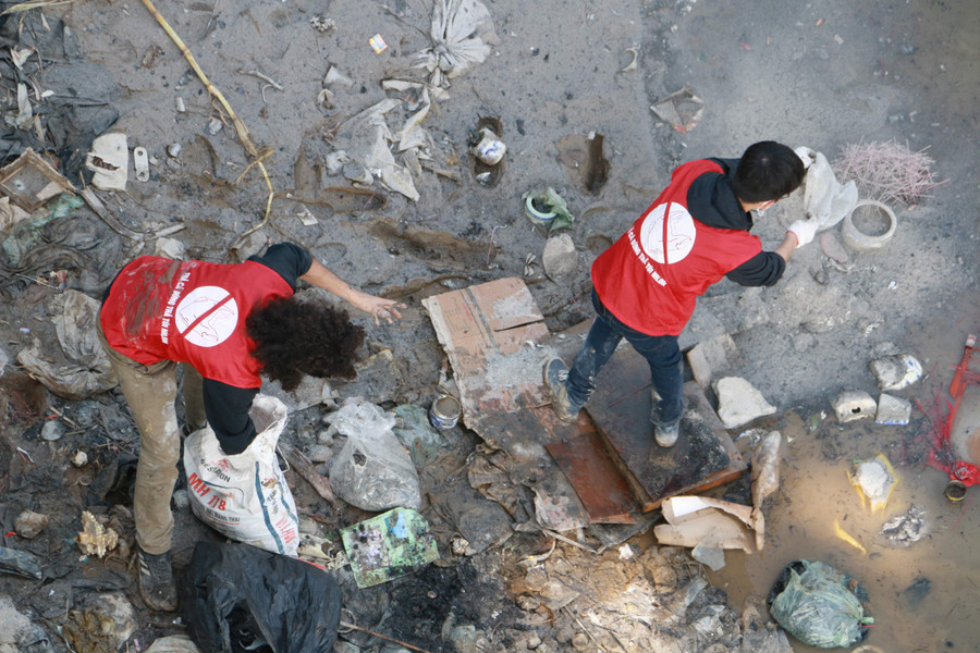 Phía bên dưới cầu, đội tình nguyên viên phải gồng mình vớt những chiếc túi nilon cùng với đồ thờ cúng lên trên bờ