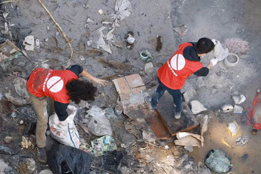 Phía bên dưới cầu, đội tình nguyên viên phải gồng mình vớt những chiếc túi nilon cùng với đồ thờ cúng lên trên bờ