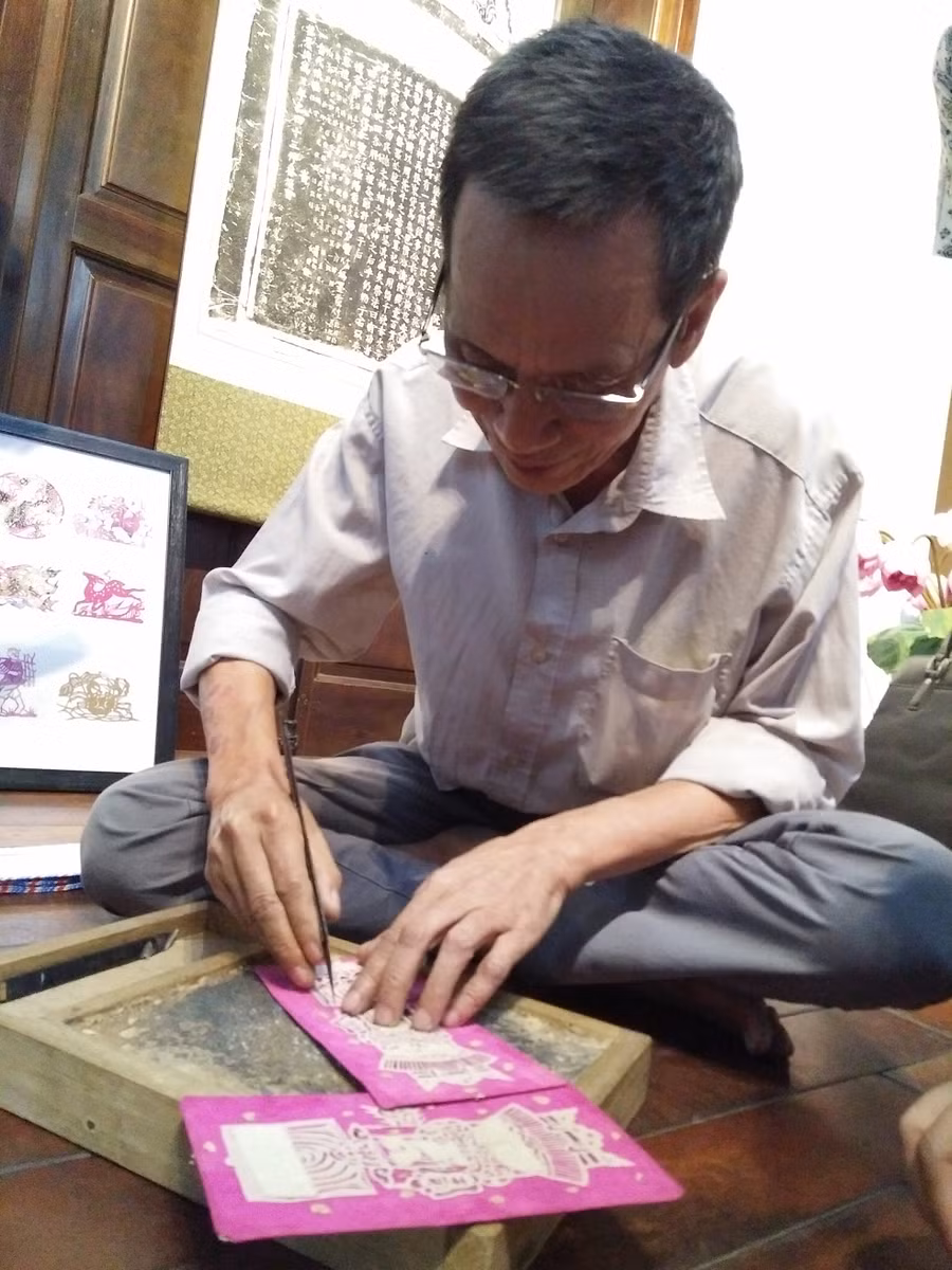 Nghệ nhân Nguyễn Đăng Giáp trình diễn dòng tranh trổ giấy - tranh dân gian Đông Hồ không còn trên thị trường. Ảnh: Bình Thanh