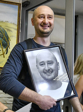 Babchenko cầm bức ảnh chân dung của mình mà các đồng nghiệp đặt tại góc tưởng niệm ôngở văn phòng kênhATR TV, Kiev hôm 31/5. Babchenko cầm bức ảnh chân dung của mình mà các đồng nghiệp đặt tại