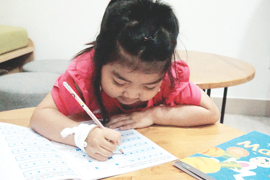 Bé Phạm Thị Kim Hoàn, 6 tuổi, năm nay chuẩn bị vào lớp 1 đang tập tô chữ cái