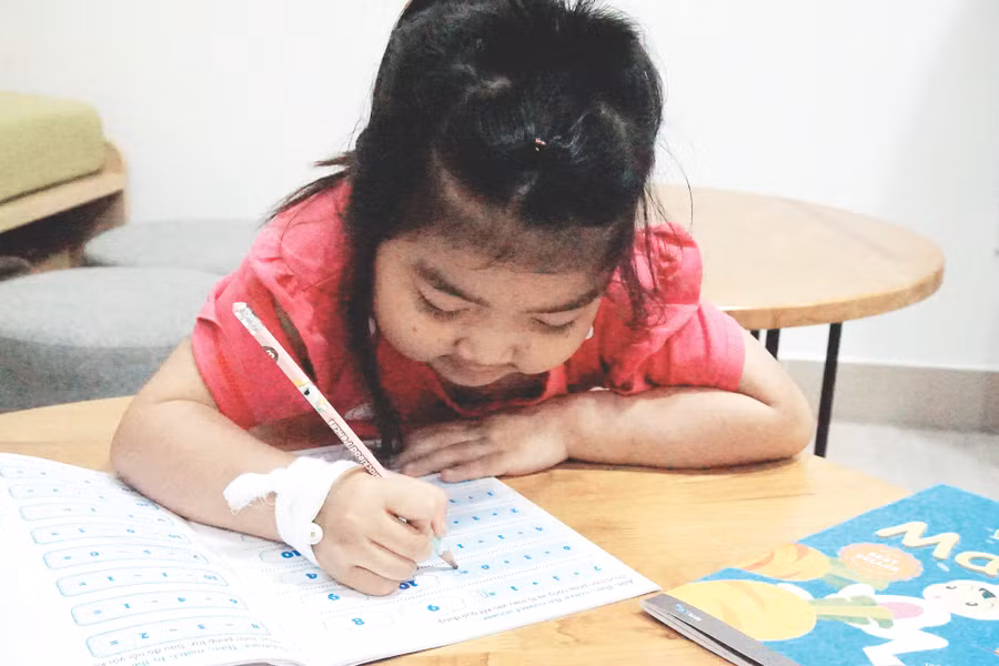 Bé Phạm Thị Kim Hoàn, 6 tuổi, năm nay chuẩn bị vào lớp 1 đang tập tô chữ cái