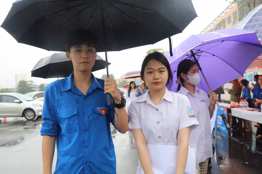 Tình nguyện viên che ô cho thí sinh tại điểm thi trường THPT Chuyên Thái Nguyên.