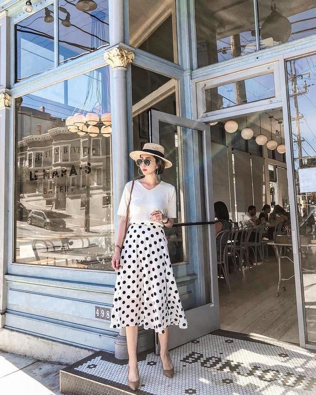 Đôi lúc cảm thấy đơn điệu với set đồ chỉ toàn màu trắng, phái nữ vẫn có thể kết hợp cùng váy họa tiết chấm bi đen, phụ kiện tông nâu ấm áp đồng điệu giữa giày và túi xách. 