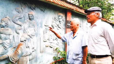 Ông Khoát dẫn khách tham quan bức tường đắp phù điêu Truyện Kiều
