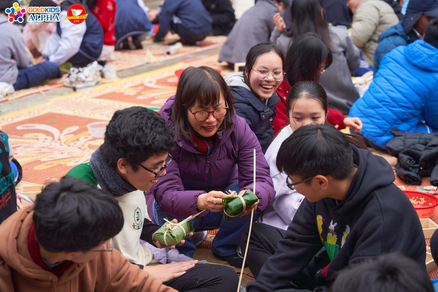 Phụ huynh hướng dẫn các em học sinh cách gói bánh chưng.