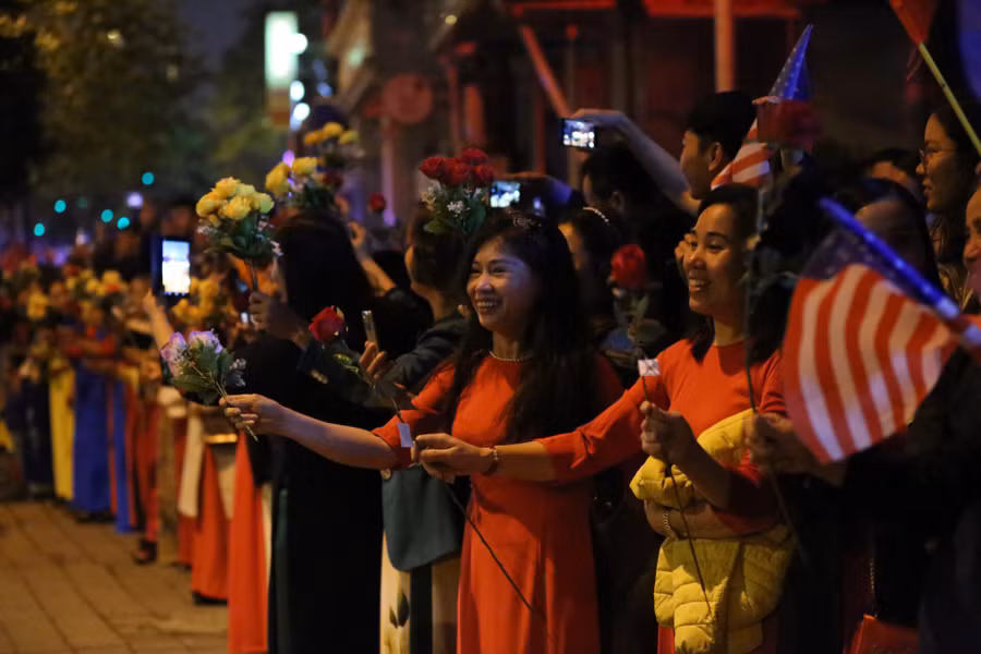 Hàng trăm người dân Hà Nội đứng hai bên đường mang theo hoa, cờ Việt Nam, cờ Mỹ chào đón phái đoàn chở Tổng thống Mỹ đi ngang. Ảnh: Thế Quang.