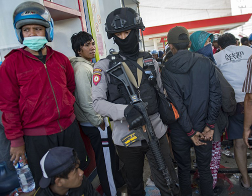 Một cảnh sát có vũ trang canh gác tại trạm xăng ở Palu. Ảnh: AFP