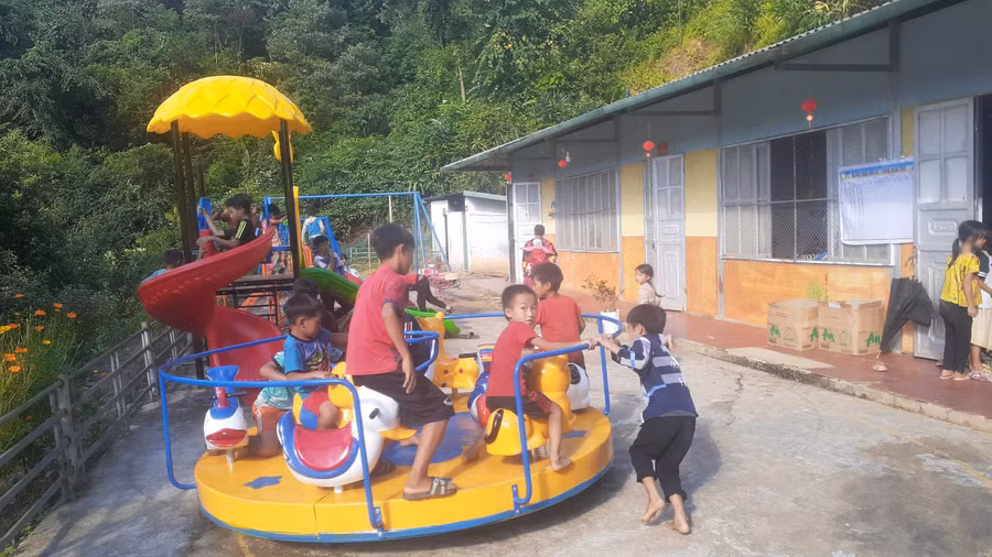 Học sinh vui đùa bên đồ chơi mới được trao tặng.