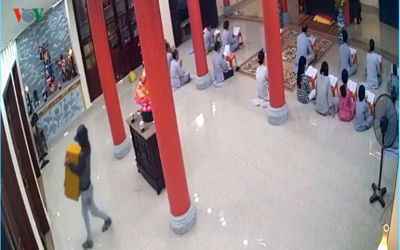 Đối tượng ngang nhiên bê thùng đựng tiền công đức ra xe.