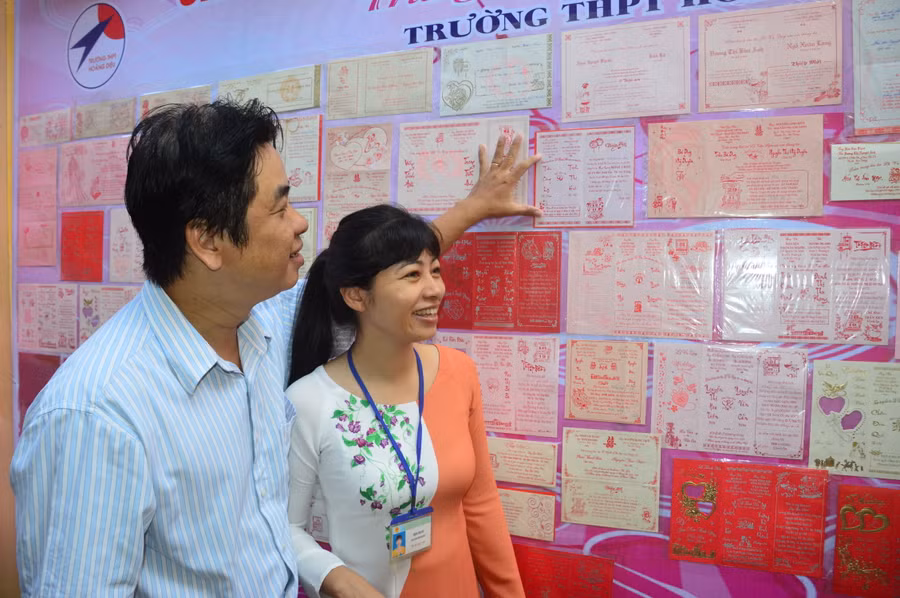 Vợ chồng thầy Trần Công Lý - cô Trịnh Thị Huê vui khi nhìn lại tấm thiệp cưới của mình