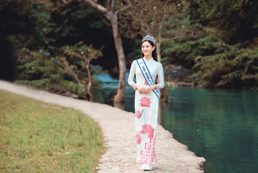 Nàng hậu trẻ trong tà áo dài trắng điểm xuyết những đóa sen hồng in nổi. Nàng hậu trẻ trong tà áo dài trắng điểm xuyết những đóa sen hồng in nổi.