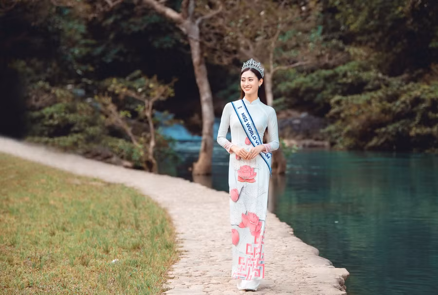 Nàng hậu trẻ trong tà áo dài trắng điểm xuyết những đóa sen hồng in nổi. Nàng hậu trẻ trong tà áo dài trắng điểm xuyết những đóa sen hồng in nổi.