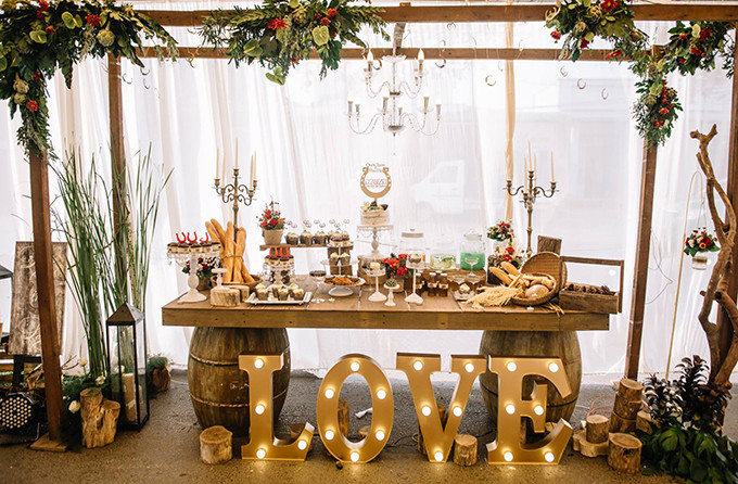 [Caption]các gam màu nâu, đỏ, xanh lá đậm từ không gian đến các loại hoa như artiso, sen đá và cả quả thông khô được bày trí cùng với những chất liệu gần gũi như gỗ, rơm, giúp không gian lễ cưới trở nên ấm cúng và thân thuộc hơn.