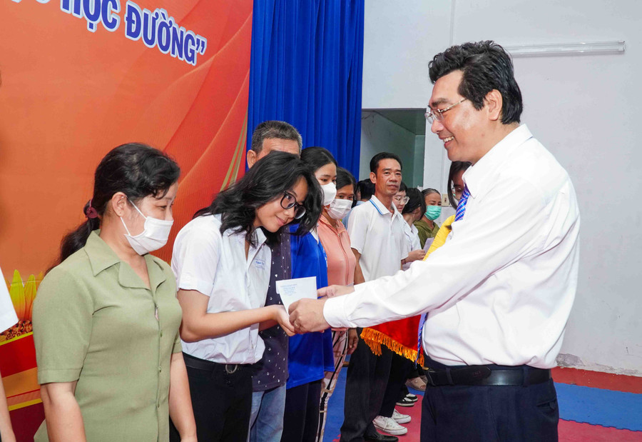 Ông Trần Thanh Bình (hình bên trái) và Thiếu tướng Nguyễn Văn Thuận trao quà cho HS.