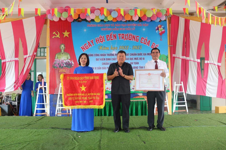 Cô Nguyễn Kim Anh (bìa trái) thay mặt nhà trường đón nhận "Cờ đơn vị dẫn đầu phong trào thi đua năm học 2021-2022" của UBND tỉnh Nam Định từ lãnh đạo huyện Hải Hậu trong lễ khai giảng năm học mới 2022-2023. Cô Nguyễn Kim Anh (bìa trái) thay mặt nhà trường đón nhận "Cờ đơn vị dẫn đầu phong trào thi đua năm học 2021-2022" của UBND tỉnh Nam Định từ lãnh đạo huyện Hải Hậu trong lễ khai giảng năm học mới 2022-2023.