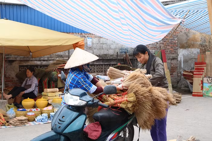 Chốc chốc lại vang lên những tiếng hỏi mua một cái chổi được bện chắc tay bằng rơm nếp còn vấn vương mùi nắng.