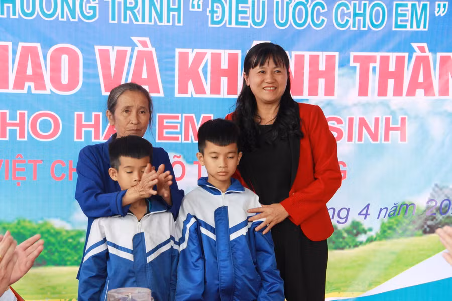 Lãnh đạo Trường Tiểu học Cẩm Duệ tặng quà cho 3 bà cháu tại buổi lễ.