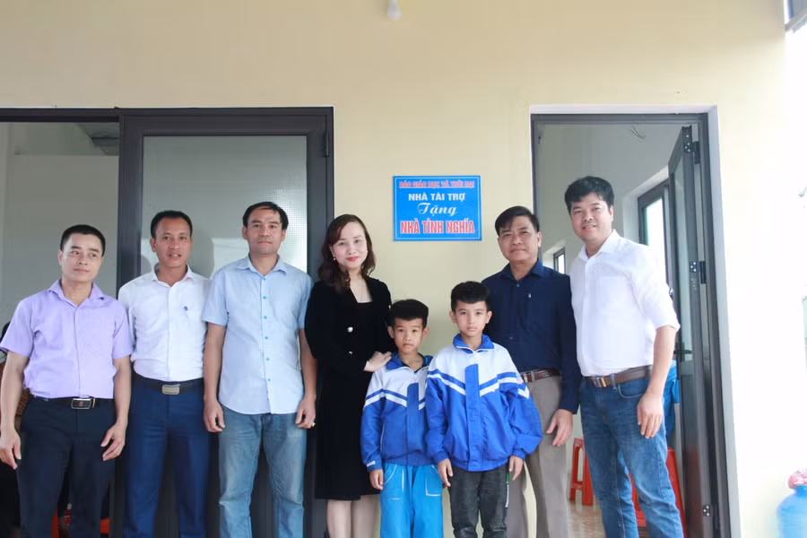 Lãnh đạo Sở GD&amp;ĐT, Báo GD&amp;TĐ khu vực Bắc Trung Bộ cùng chính quyền địa phương chụp ảnh kỷ niệm với hai cháu tại căn nhà vừa hoàn thành.