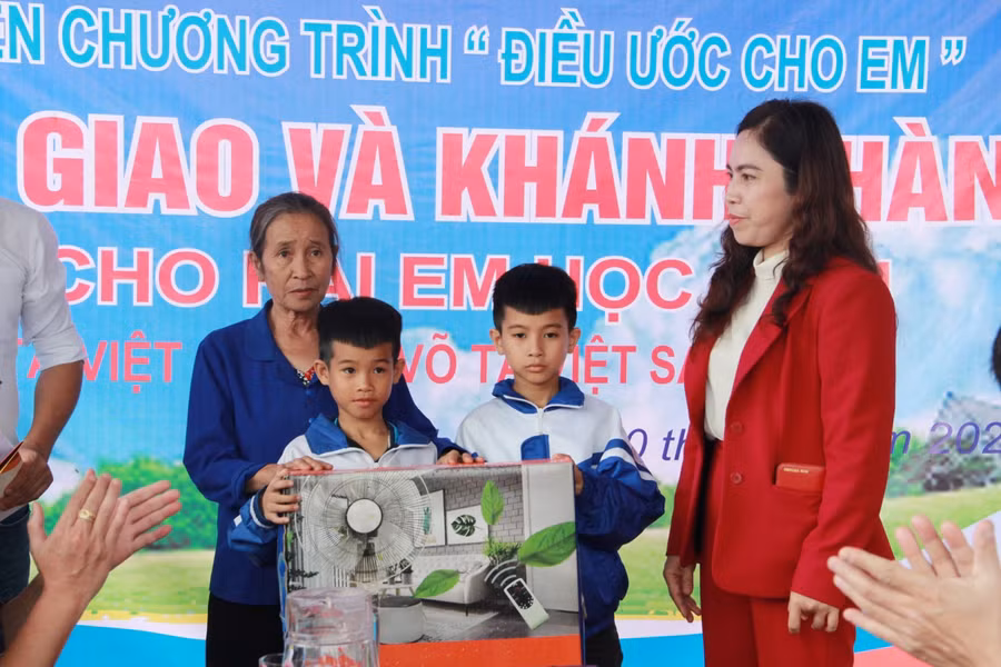 Đại diện Công ty Cổ phần đầu tư Môi trường Việt Nam Xanh tặng chiếc quạt điện cho 3 bà cháu.