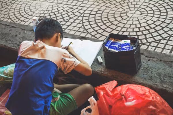 Hình ảnh mẹ cầm tay con dạy từng nét chữ bên lề đường gây xúc động mạnh