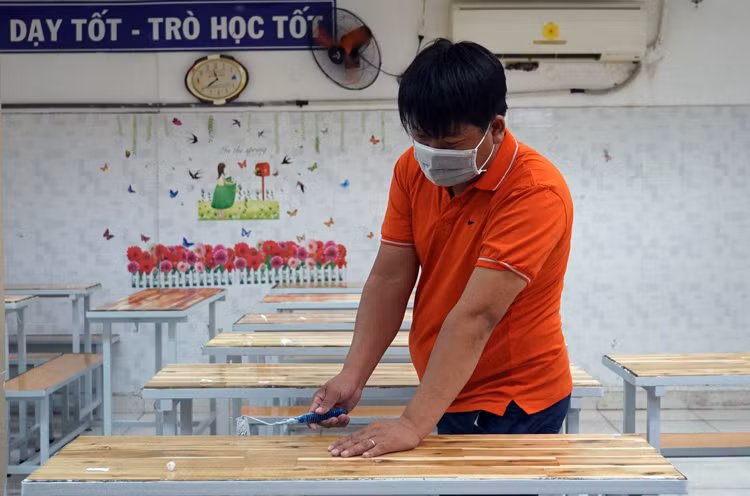 Nhân viên trường THCS - THPT Hồng Hà sơn lại bàn ghế học sinh. Ảnh: Mạnh Tùng.