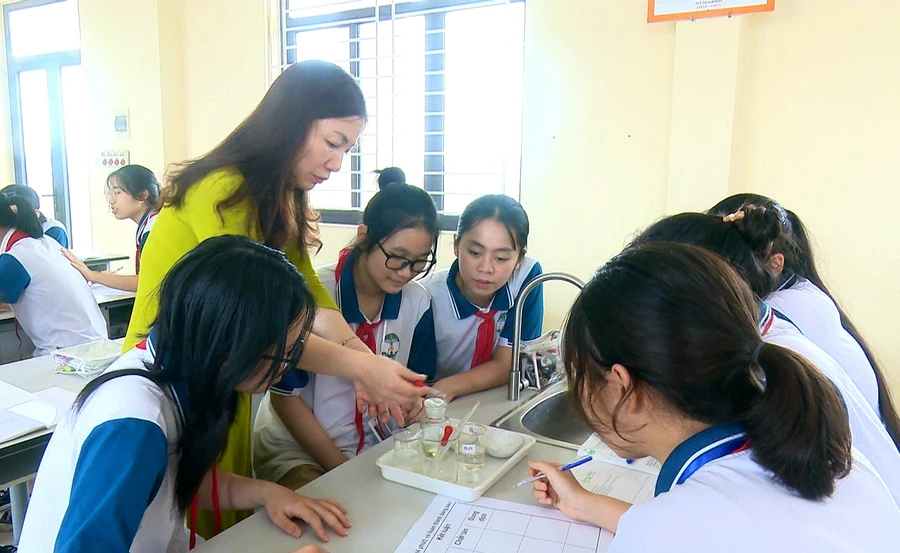 Cô Hòa và các em học trò trong một giờ thực hành môn Hóa học tại trường.