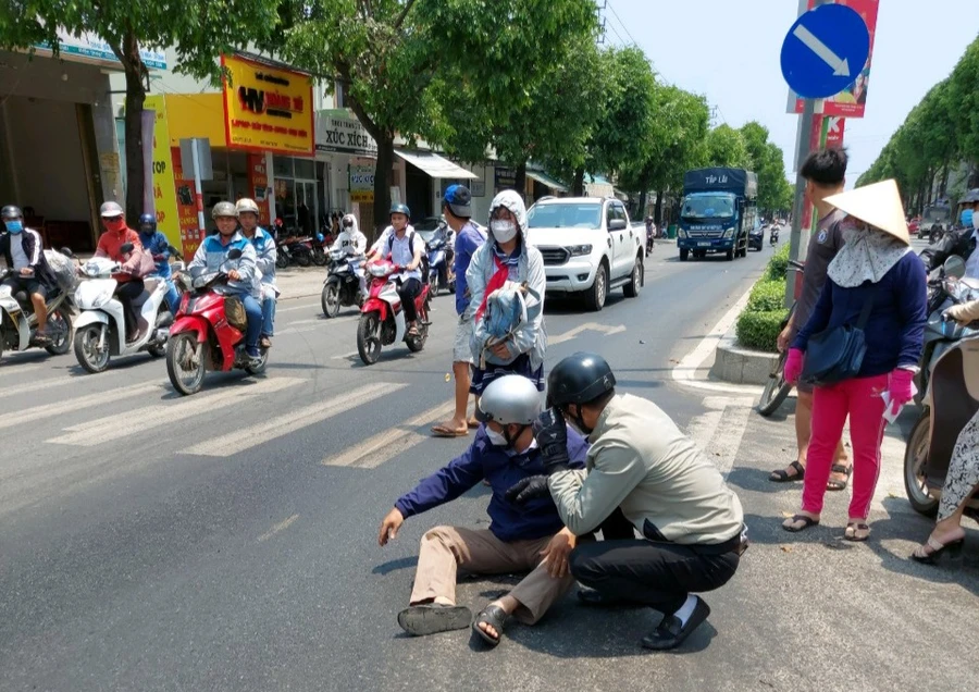 Phụ huynh đón con đi học về bị té ngã do vệt dầu nhớt đổ trên đường.