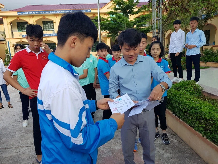 Thầy Tập (bên phải) phát thẻ dự thi kì thi chọn học sinh giỏi cấp tỉnh cho các em học sinh. Ảnh: NVCC