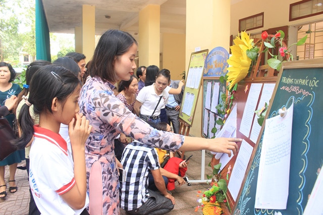 Giáo viên và học sinh tham quan trưng bày chữ viết.