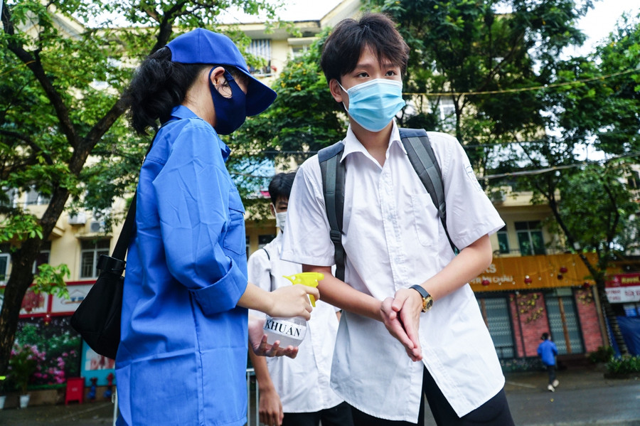 Tình nguyện viên đứng hỗ trợ thí sinh sát khuẩn tay.