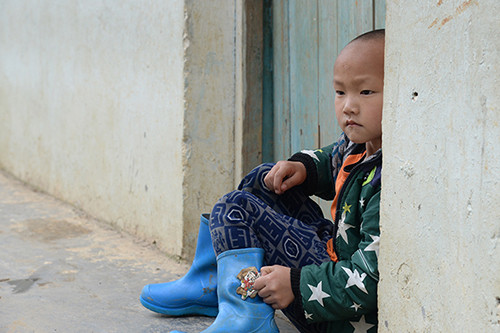[Caption]A boy sits in front of a door in Hechi, Guangxi, on April 20. The boy is one of 200 students at Shang Zhen primary school, where most of the children have parents who have left for work in Chinas bigger cities. Photo: Visual China