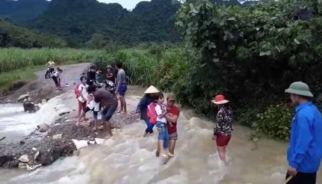 Các em phải được người lớn bế qua suối nước chảy xiết.